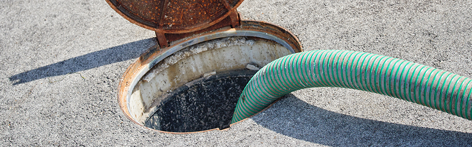 Green hose pumping water from an open manhole.
