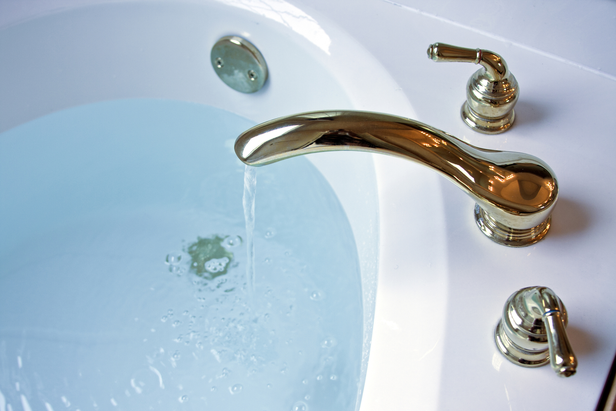 Chrome faucet with water running into the bathtub